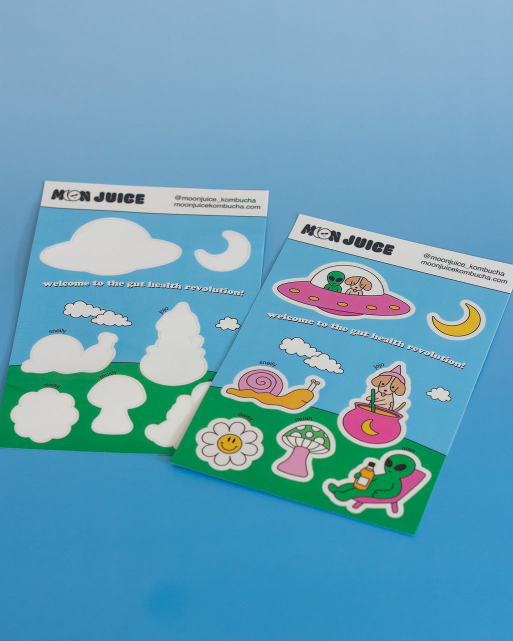 Two sheets of stickers with Moon Juice Kombucha designs on a blue background, one empty and one full.