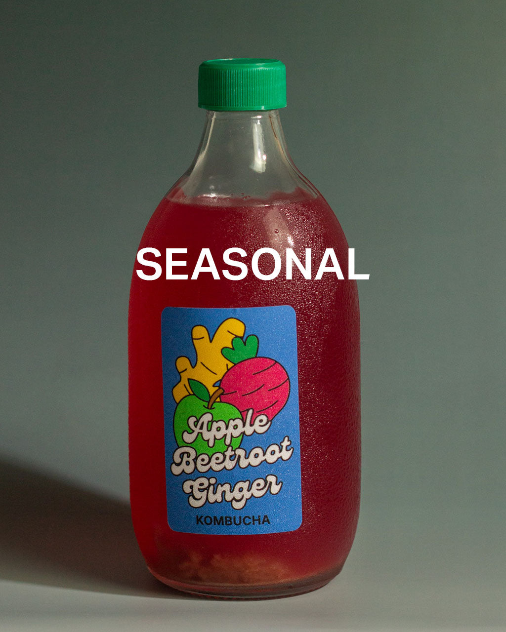500ML Bottle of Apple Beetroot Ginger kombucha with a pink cap on a dark teal gradient background, with the caption "SEASONAL"