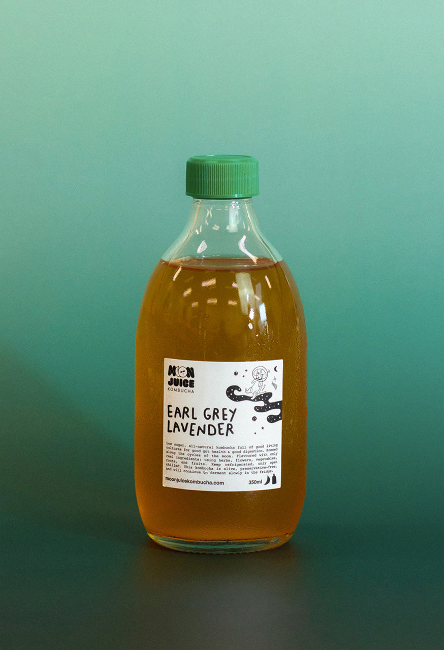 Bottle of 'Earl Grey Lavender' kombucha with a green cap on a teal gradient background