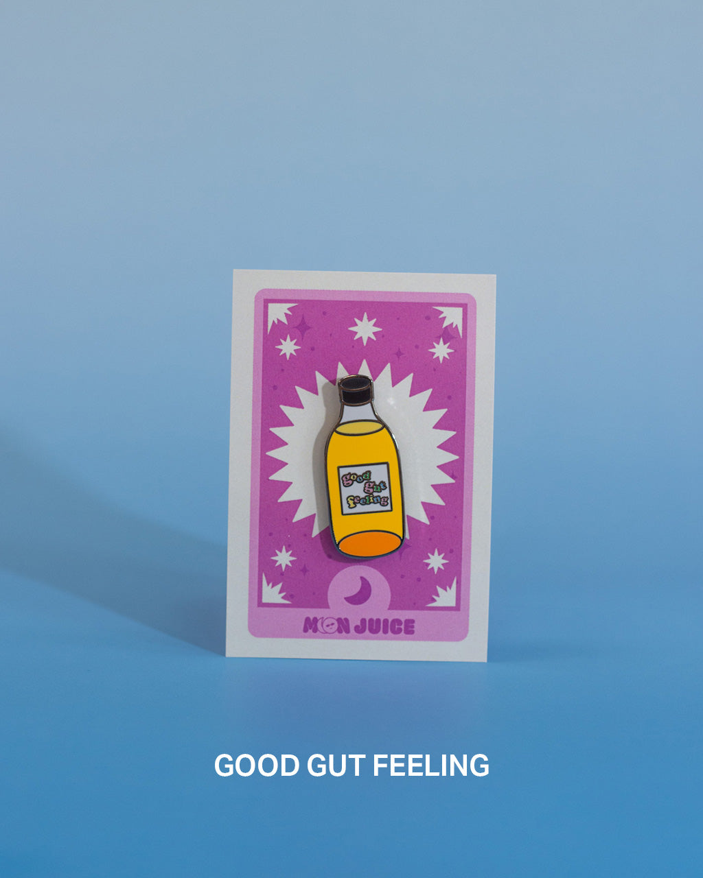 Enamel pin with a bottle design that says "good gut feeling" on a pink tarot card against a blue gradient background