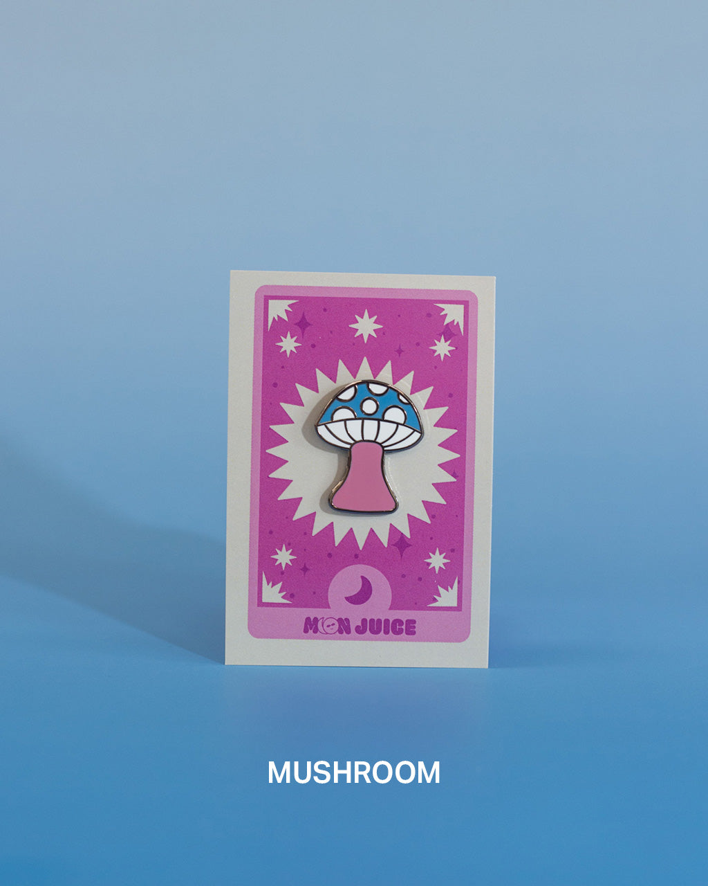 Enamel pin with a mushroom design on a pink tarot card against a blue gradient background