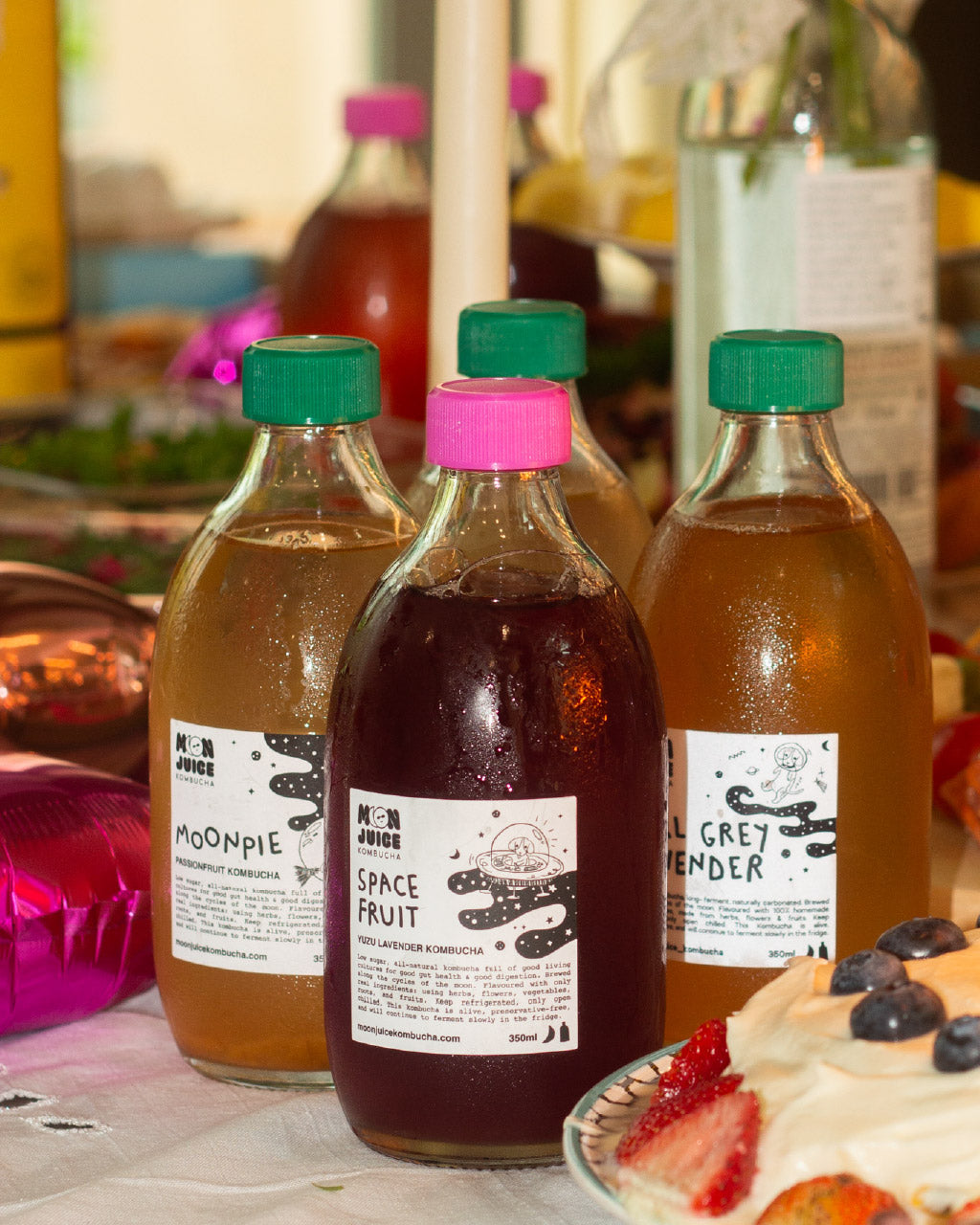 4 Moon Juice Kombucha bottles on a party table setting