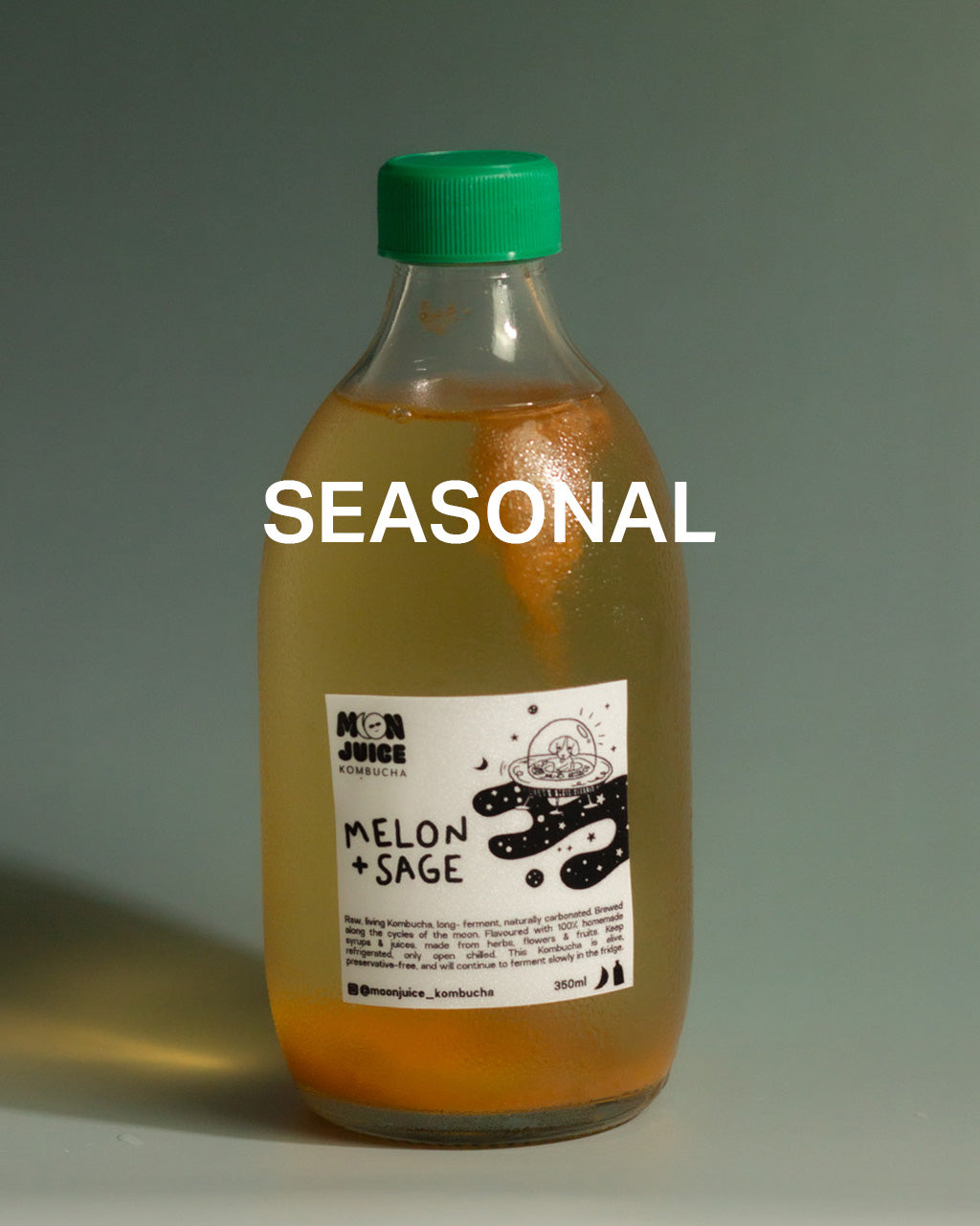 350ML Bottle of melon + sage kombucha with a green cap on a dark teal gradient background, with the caption "SEASONAL"