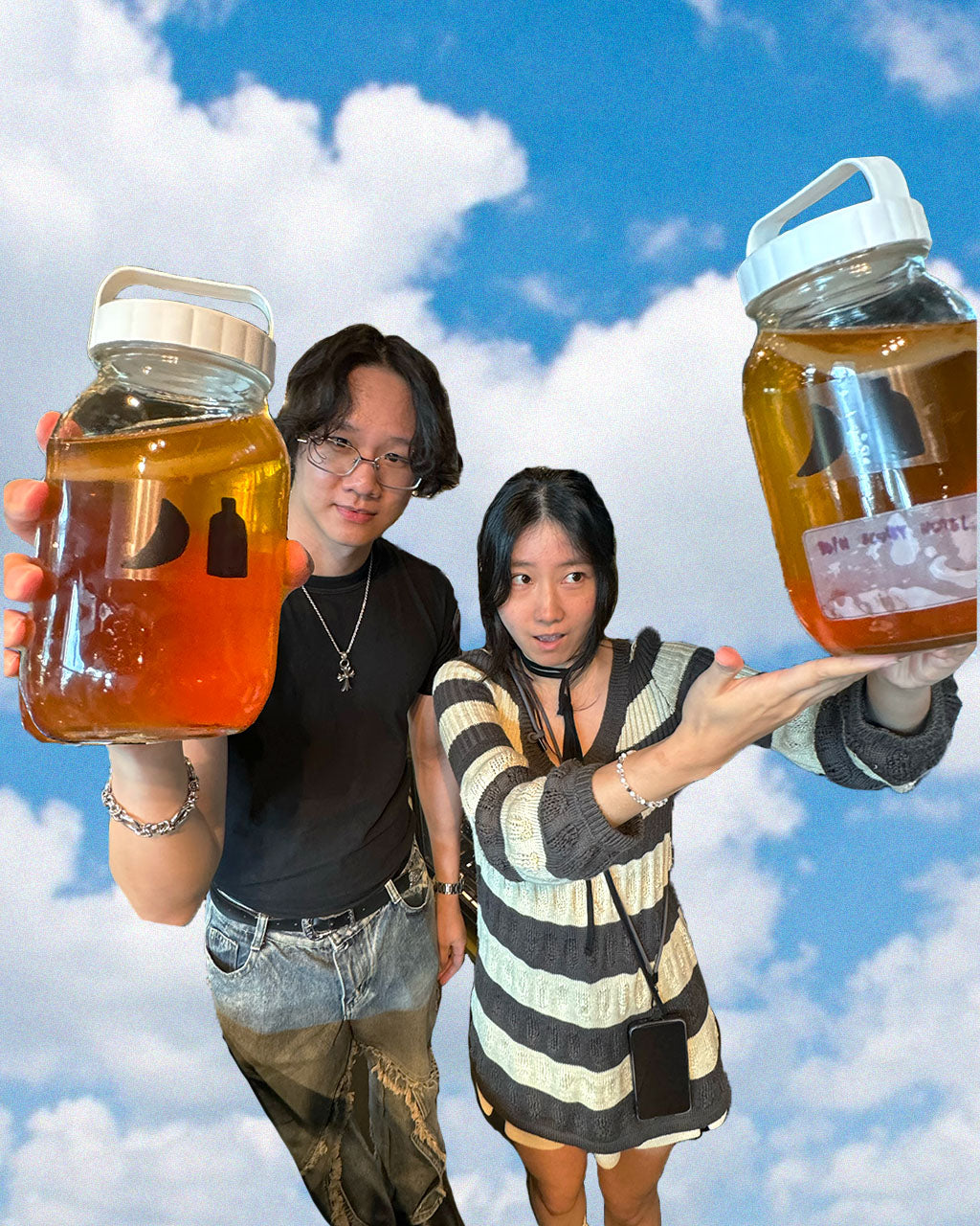 Two people holding jars of kombucha edited against a blue sky background.