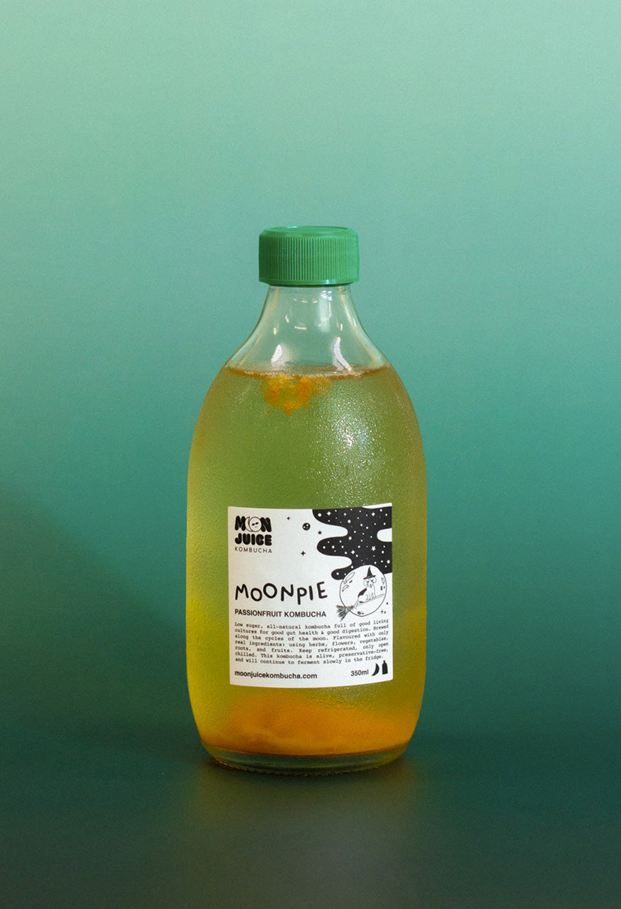 Bottle of 'Moonpie' kombucha with a green cap on a teal gradient background