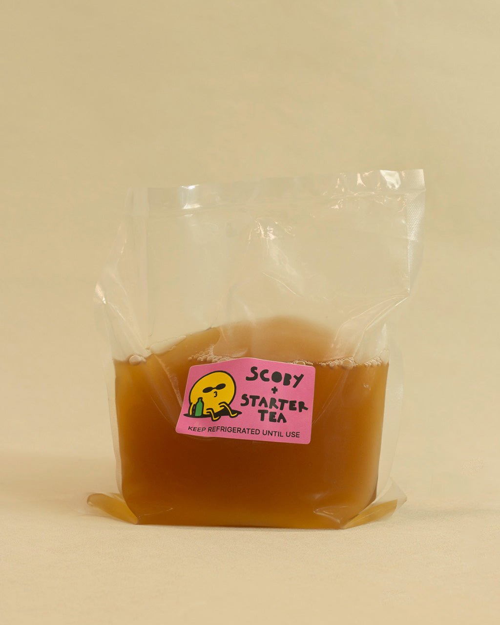 Packaged scoby + starter tea with a pink label on a beige background