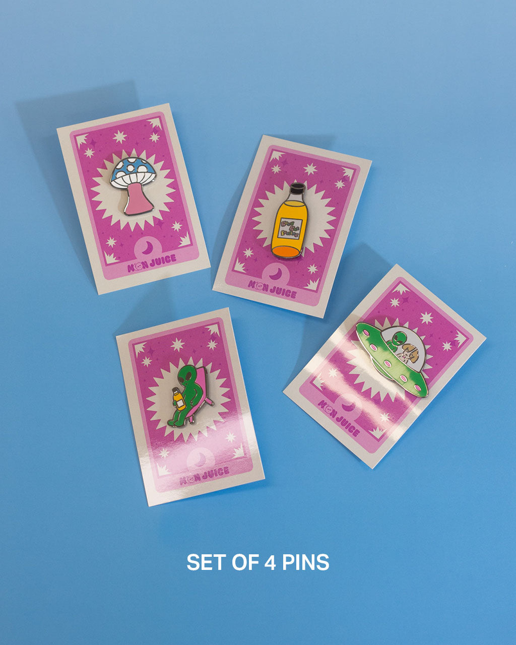 Set of four colorful enamel pins with various designs on pink tarot cards against a blue background