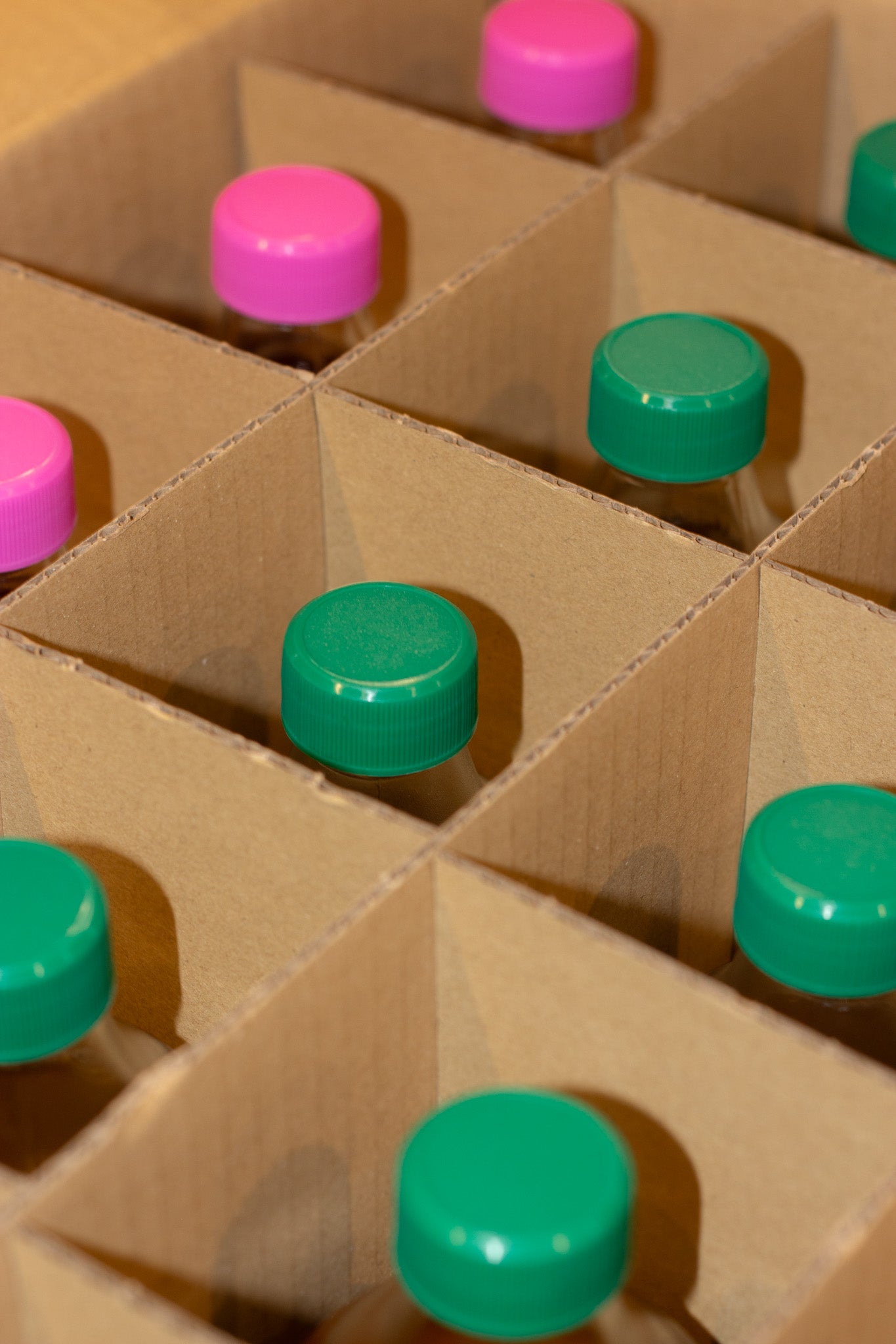 Close up of a cardboard box with green and pink lids arranged in a grid.