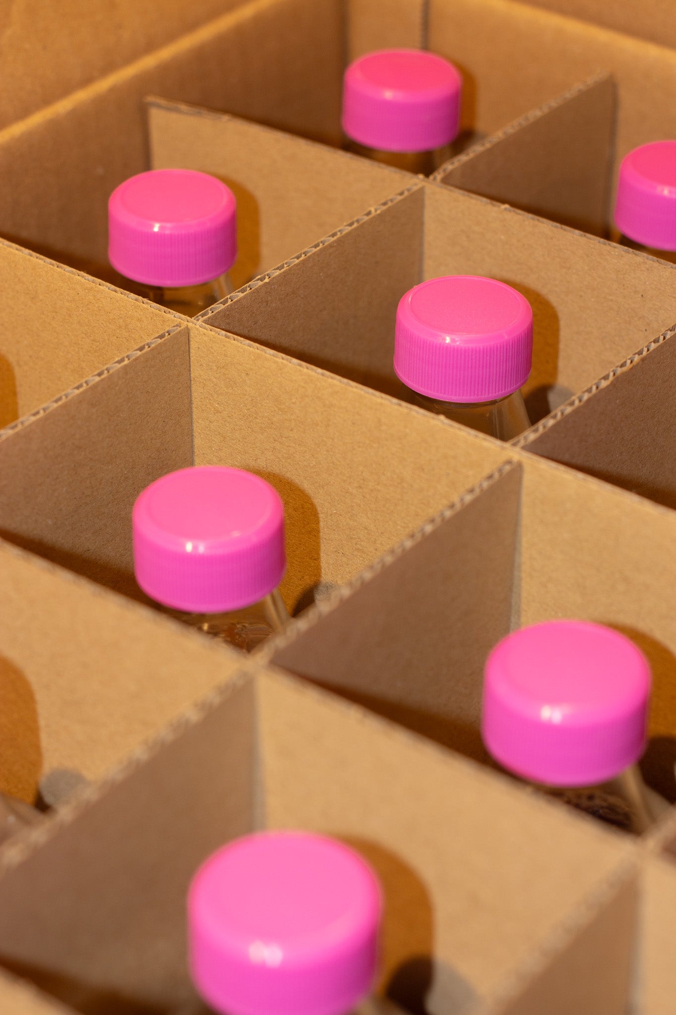 Close up of bottles with pink caps arranged in a cardboard box