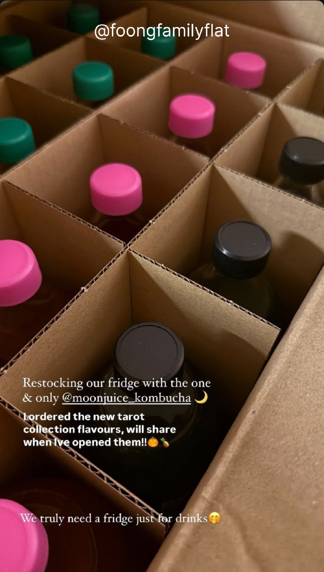 Closeup of a box full of Moon Juice kombucha bottles with striking black, pink, and green bottle caps. Taken by @foongfamilyflat