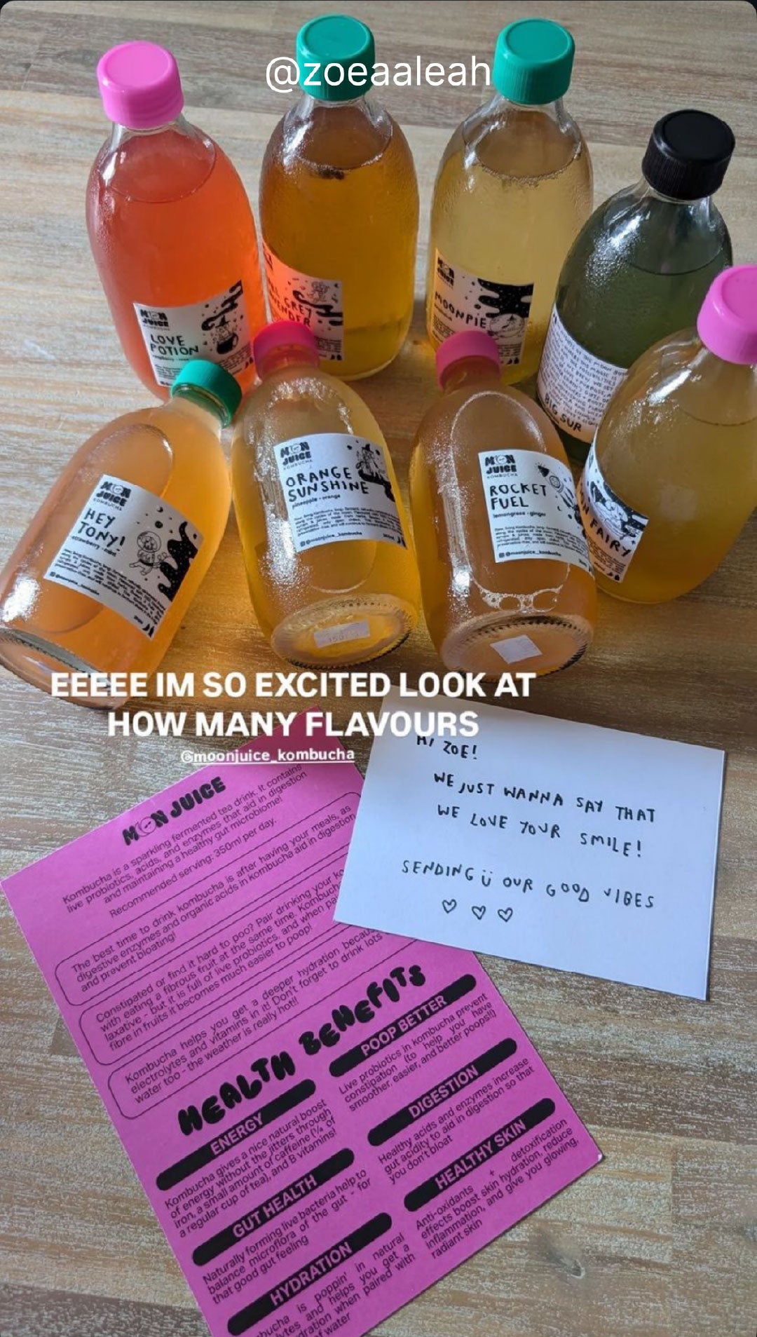 Flatlay of 8 Moon Juice Kombucha bottles, along with an informational product brochure and a handwritten note, taken by @zoeaaleah
