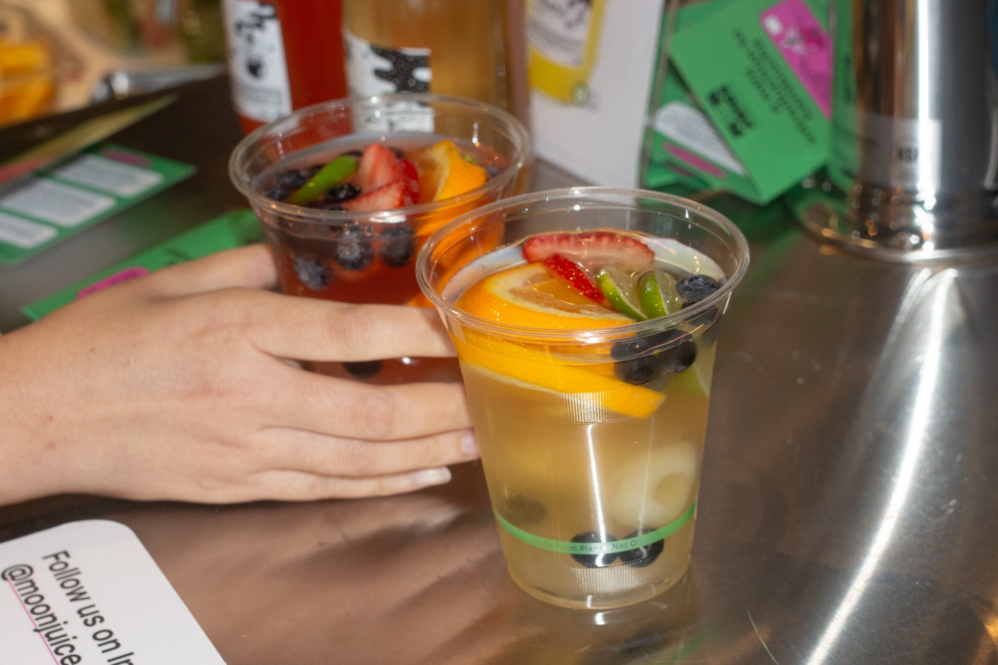 A menu "kombucha mocktail cart" with instructions on how to "build your own mocktail kombucha", next to various fruit toppings in different square containers.