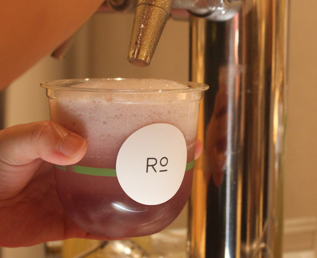 Close-up of kombucha being dispensed from our cart for Romi's store event. Featuring custom branded cups.