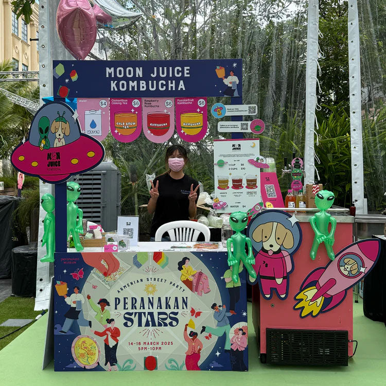 Our kombucha booth at the Armenian Street Party 2025 for Peranakan Museum, featuring our kombucha cart, and lots of illustrated foam board cutouts with our branding!