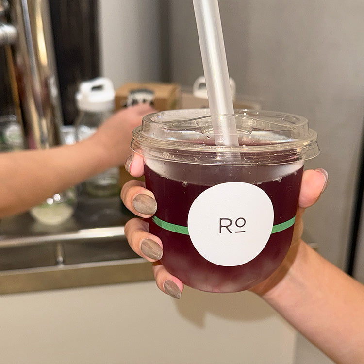 Guest holding a cup of purple kombucha with custom Romi-branded sticker