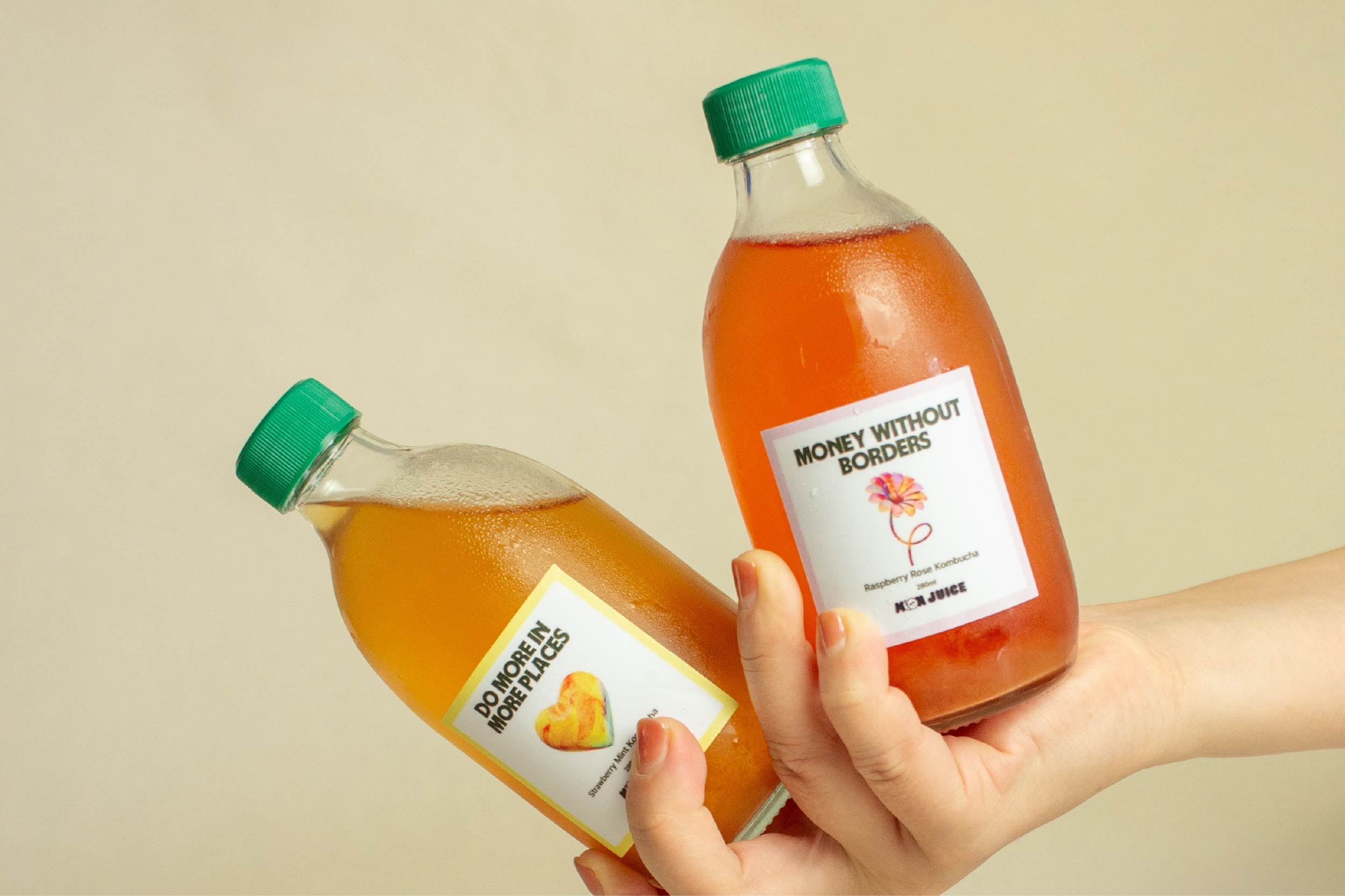 two bottles of customised kombucha for Wise, held against a beige background